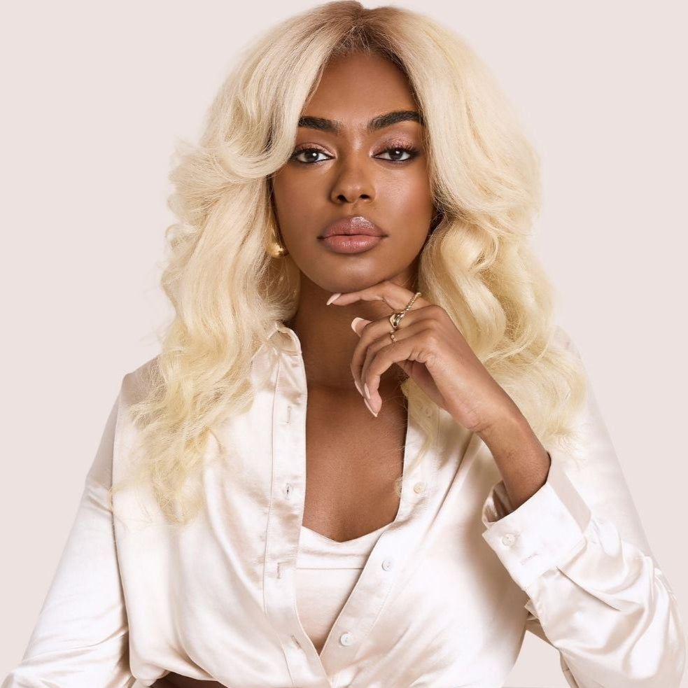 A striking woman with voluminous luxury textured hair extensions in a radiant blonde shade. Her bouncy, defined curls frame her face beautifully as she poses elegantly in a satin cream two-piece outfit, exuding confidence and sophistication. These high-quality luxury textured hair extensions provide fullness, length, and effortless movement, seamlessly blending for a glamorous and natural look.