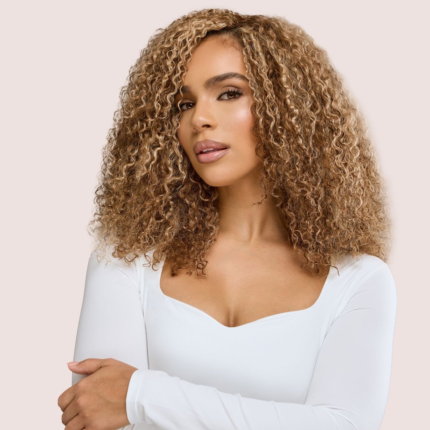 A woman with beautifully defined, golden brown kinky curly hair extensions, styled in a voluminous, natural look. These luxury textured hair extensions blend seamlessly with her natural curls, enhancing fullness and movement. The rich, warm brown tones highlight the intricate curl pattern, creating a soft yet bold statement. The high-quality extensions add body and dimension, perfect for an effortlessly glamorous style.