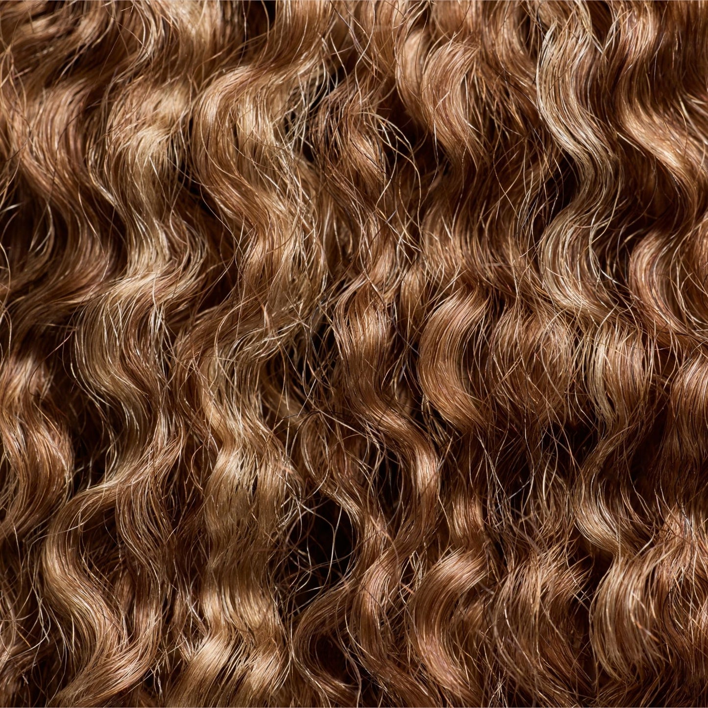 A close-up image of kinky curly textured hair extensions in a stunning golden espresso shade. The rich brown hue with warm undertones enhances the tight, springy curl pattern, creating a natural and voluminous look. These high-quality hair extensions for Black women blend effortlessly with natural curls, offering a perfect option for protective styling and added fullness.