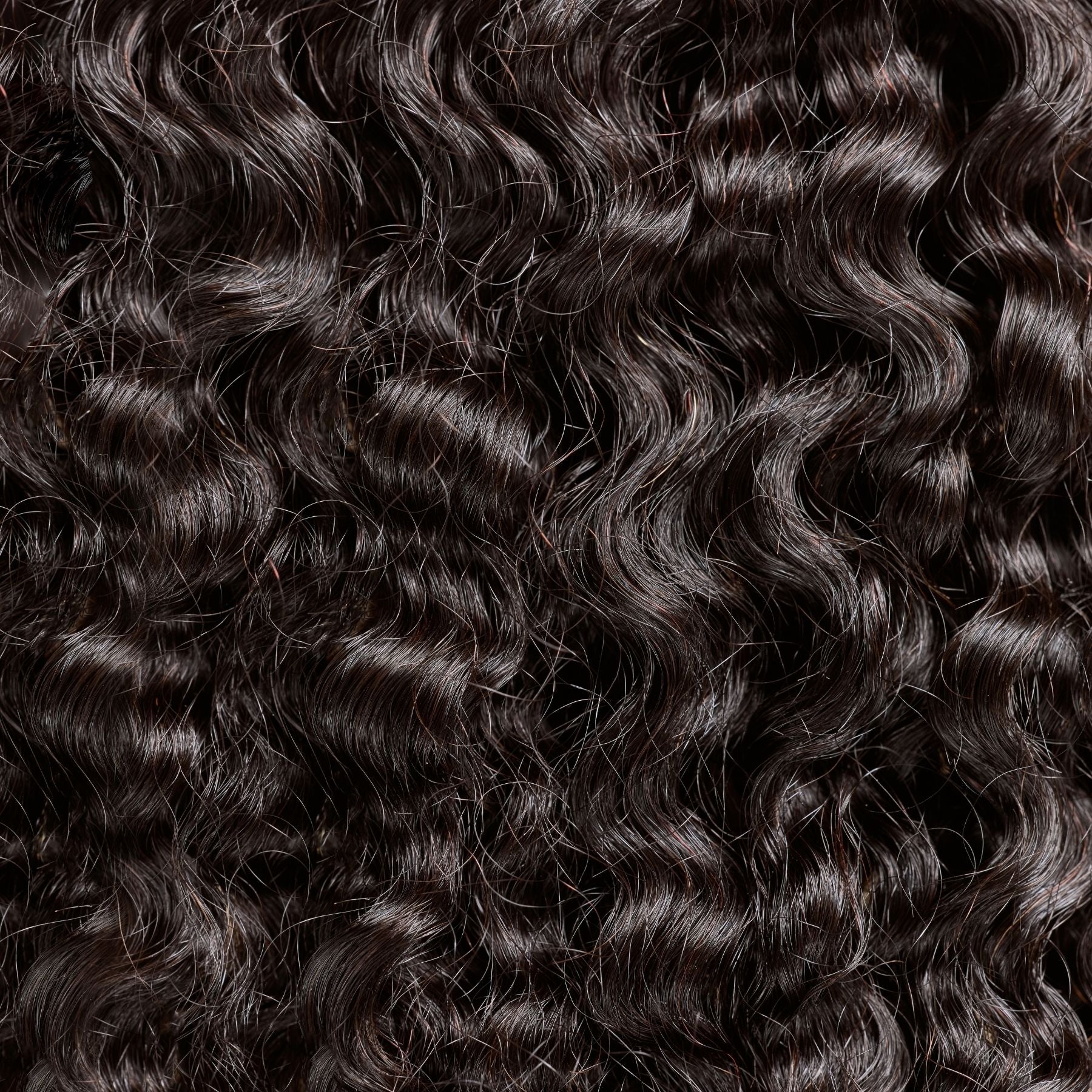 A close-up of kinky curly textured hair extensions in a rich natual black shade, featuring tightly coiled curls for maximum volume and definition. These premier textured hair extensions mimic the natural beauty of coily hair, offering a soft, lightweight feel and a bouncy, full-bodied look. The high-quality strands enhance texture while providing a seamless blend with natural hair, making them ideal for achieving a flawless, natural style