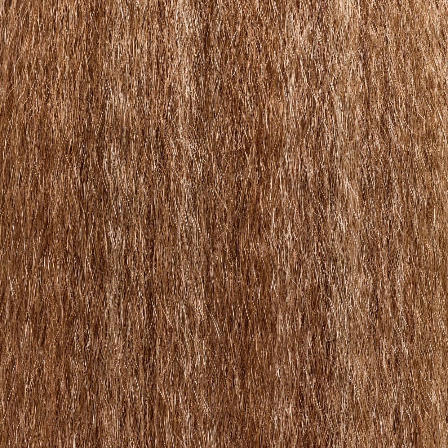 A close-up texture photo of golden brown kinky straight hair extensions, highlighting the soft yet voluminous strands that mimic natural, blown-out coarse hair. The premier textured hair extensions provide a seamless blend with natural hair, offering a thick, full-bodied look with a natural sheen. The intricate details showcase the high-quality fiber and realistic texture, perfect for styling versatility.