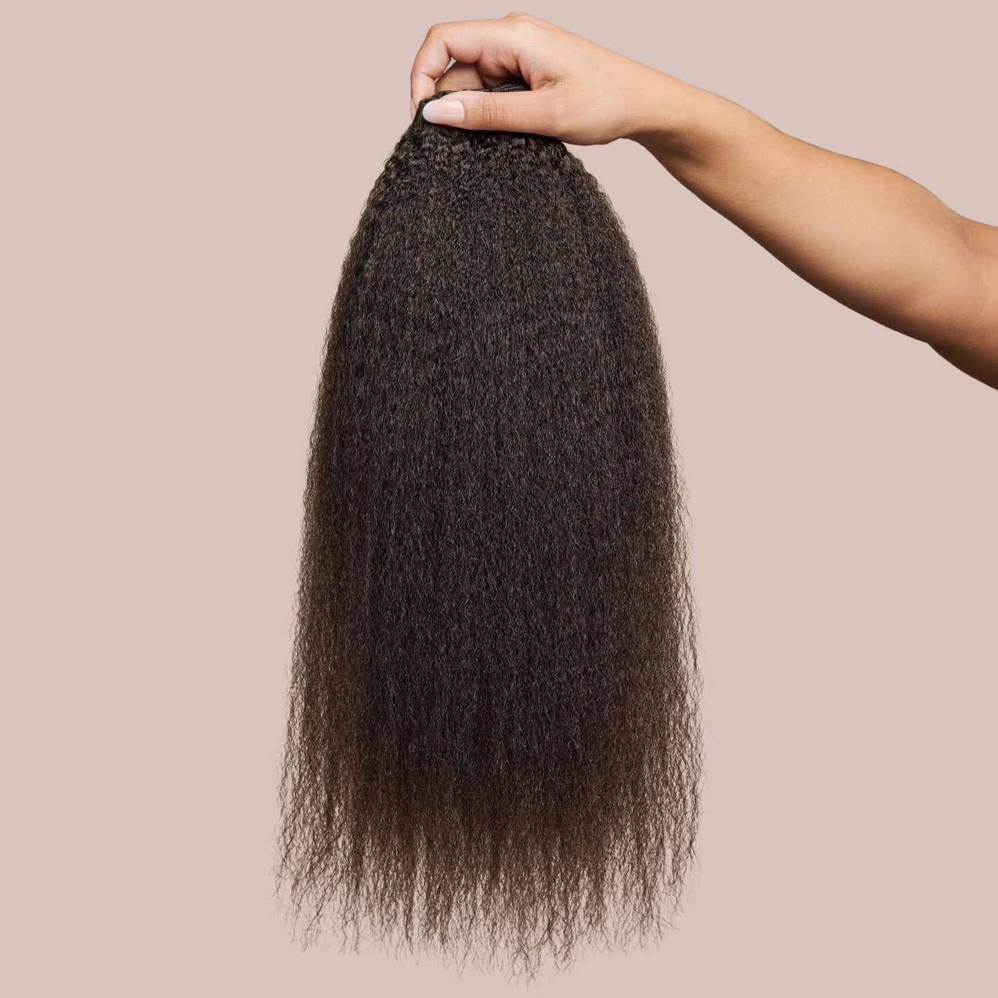 A hand holding a bundle of kinky straight hair extensions in a natural black shade, showcasing its thick, textured strands with a soft, blown-out finish. The deep, rich black color enhances the natural sheen, mimicking the look of African American hair that has been gently straightened. These luxury textured hair extensions provide volume, length, and versatility for protective styling, making them a premium choice for a seamless and natural blend.